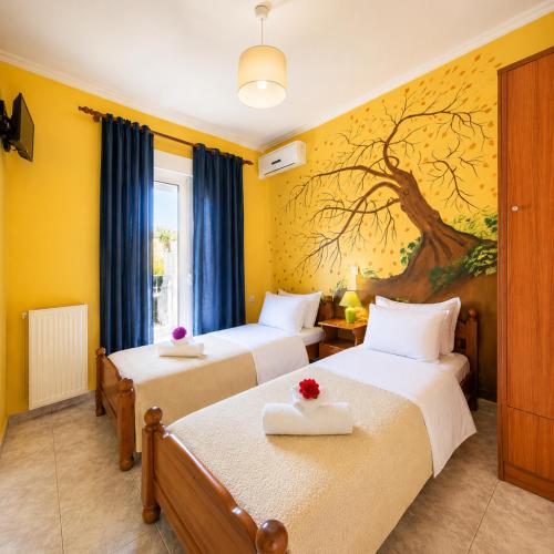 two beds in a room with a tree mural on the wall at Sunset Apartments in Missolonghi