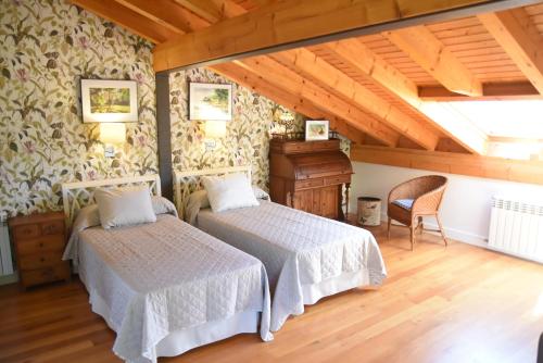 two beds in a room with wooden ceilings at Villa La Pinpa in Bárcena de Cicero