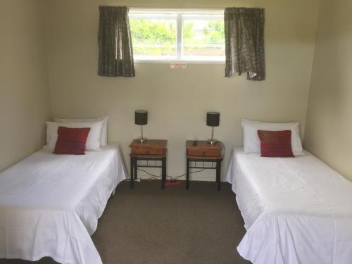 two twin beds in a room with a window at Orewa Pillows Lodge in Orewa