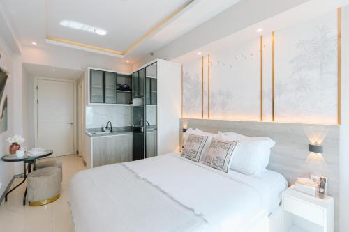 a bedroom with a white bed and a kitchen at Yoonah at Benson Pakuwon Mall in Lontar