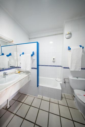 a bathroom with a tub and a sink and a toilet at Hotel Playa Bocaina in Mojácar