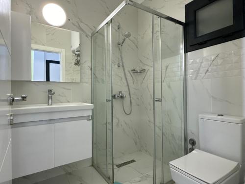 a bathroom with a shower and a toilet and a sink at Caesar Resort & Spa Collection Studios Pools & Long Beach in Iskele
