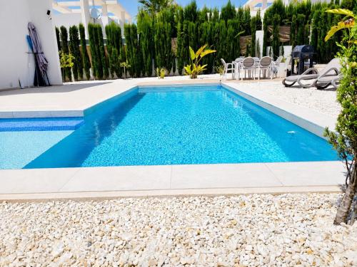 a swimming pool in a villa with blue water at La Perla Blanca in Benijófar