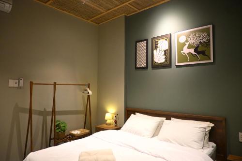 a bedroom with a bed with three pictures on the wall at Mer Home in Tây Ninh