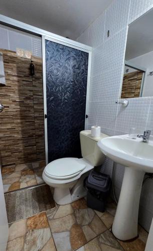 a bathroom with a toilet and a shower and a sink at Hotel Internacional in Tacuarembó