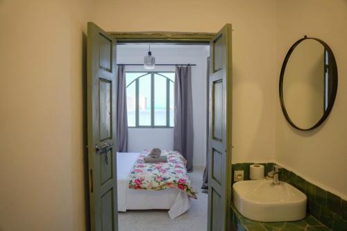 a bathroom with a bed and a sink and a mirror at Sand House in Imsouane