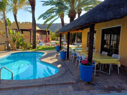 a resort with a swimming pool and tables and palm trees at Capbon Guesthouse in Windhoek