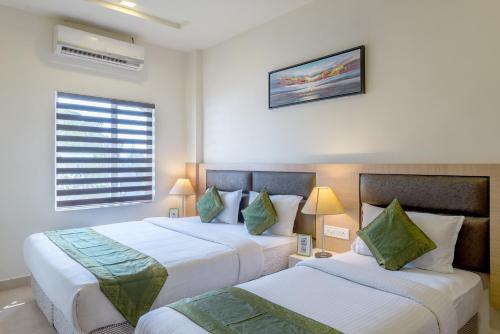 a hotel room with two beds and a window at Treebo Nestlay Airport Alandur in Chennai