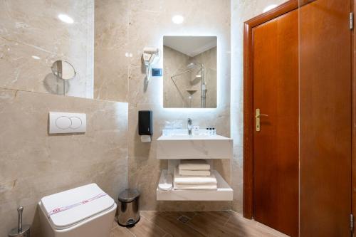 a bathroom with a sink and a toilet and a mirror at Hotel Montenegrino in Tivat