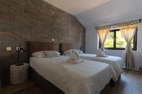 two beds in a bedroom with a brick wall at Rezidenca Ortus in Ankaran