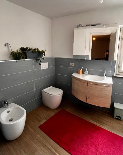 a bathroom with a red rug and a sink and a toilet at Casa Stella in Venzone