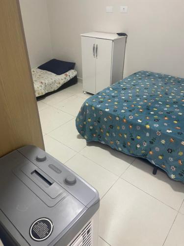 a room with a bed and a refrigerator in it at Casa aconchegante centro in Peruíbe