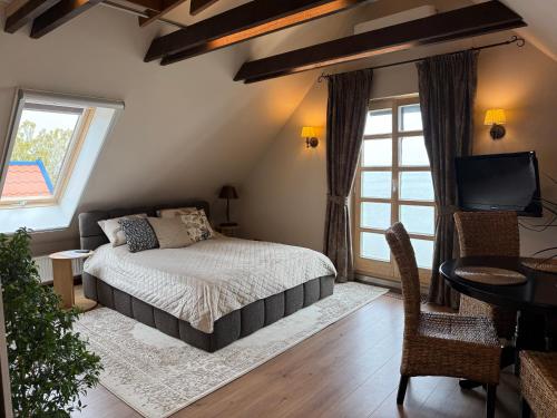 a bedroom with a bed and a desk and a television at Vila Preiloja in Neringa