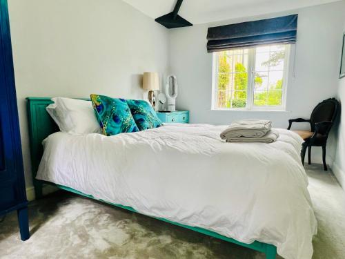 a bedroom with a large white bed with blue pillows at The Priory Cottage in Legbourne