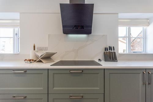 a kitchen with green cabinets and a counter top at Stretton Lower hall in Malpas