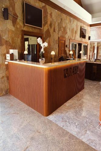 a lobby with a reception desk with a television on a stone wall at Varaya Resort in Ban Kraek