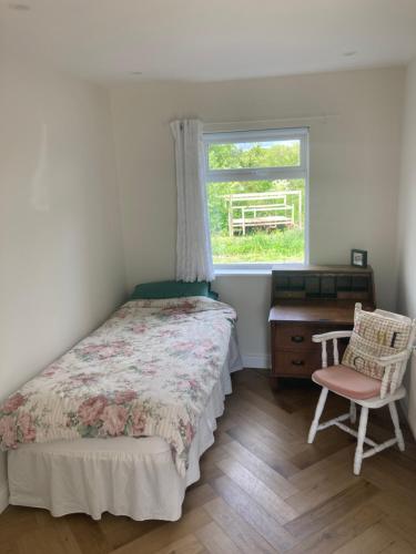 a bedroom with a bed and a desk and a window at 3 bedroom Beautiful Cosy Cottage in Killashandra