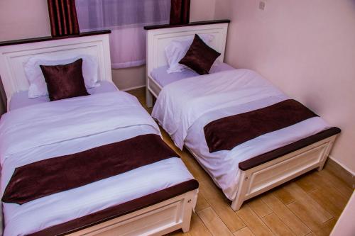 two beds in a small room withskirts at Makenahluxuries Embu Paradise Apartment near Java Gakwegori in Kangaru