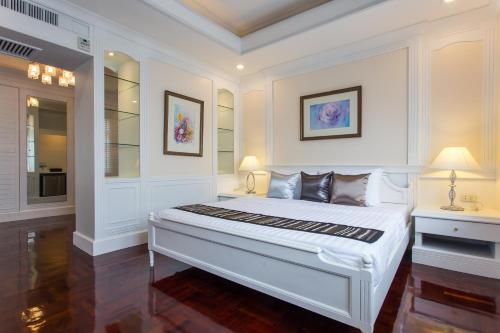 a bedroom with a large white bed with two lamps at The Lek Aree in Bangkok