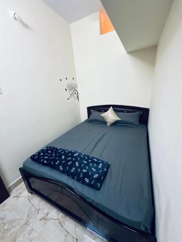 a small bedroom with a bed with blue sheets at Wee Homes in Bangalore