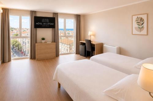 a hotel room with two beds and a desk at Hôtel de l'Étoile in Antibes