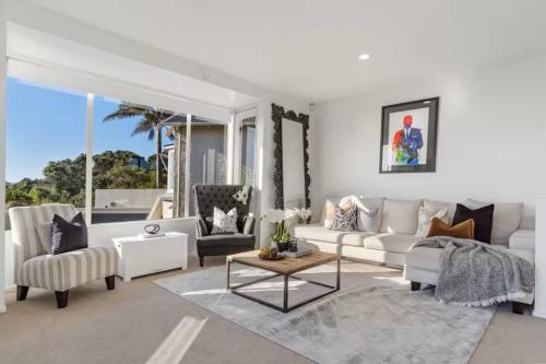a living room with white furniture and a large window at Ocean view Designer Standalone Villa Big Deck in Auckland