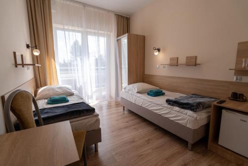 a room with two beds and a table and a tv at Łazienki Uzdrowiskowe Nr 1 in Ciechocinek