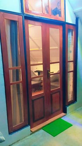 a front door of a house with a green mat at Ella Kumi Wood Cabin in Ella