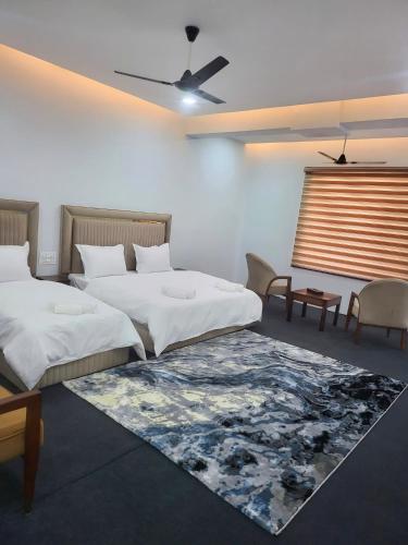 a bedroom with two beds and a rug at Nirvana Stay & Gaming Zone in Bhadarwāh