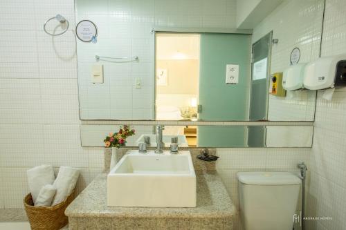 a bathroom with a sink and a toilet and a mirror at Rede Andrade Itabuna in Itabuna