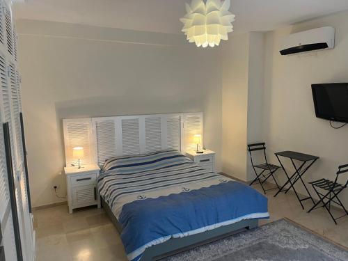 a bedroom with a bed and two tables and a tv at New 2-room secure residence, beach, pool in Port El Kantaoui