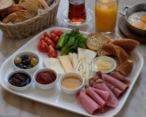 a plate of food with meats and cheese and bread at Nenessa Airport Hotel in Arnavutköy