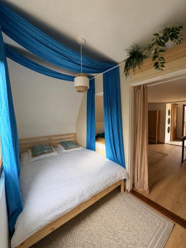 a bedroom with a canopy bed with blue curtains at Szőlők közt Apartman in Dunaszentmiklós