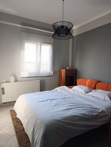 a bedroom with a large white bed and a chandelier at Raphael Guesthouse in Tríkala