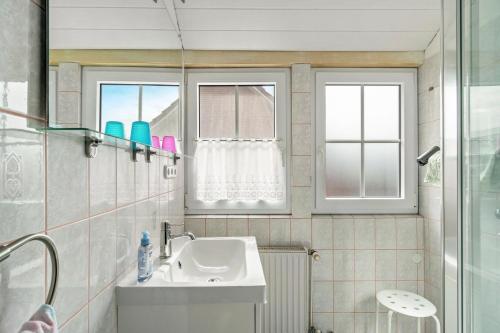 a bathroom with a sink and two windows at An't Fischerspad in Wangerland