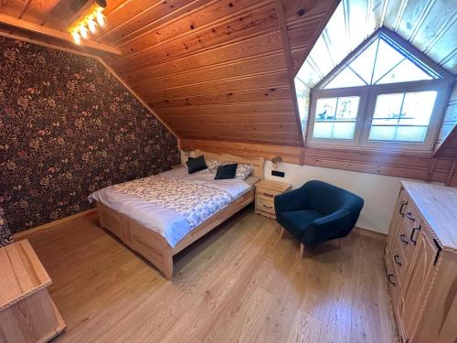 a bedroom with a bed and a window and a blue chair at Apartament Łostówka in Łostówka