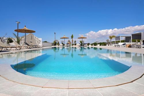 a large swimming pool with blue water and umbrellas at Cape Serenity Mansion in Ayia Napa