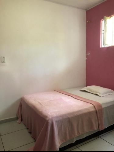 a bed in a room with a red wall at Lar sossego Itabuna in Itabuna