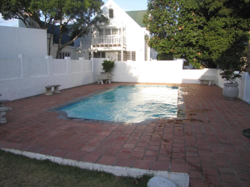 una piscina en un patio trasero con un patio de ladrillo en Holiday Home Our Happy Place, en Plettenberg Bay