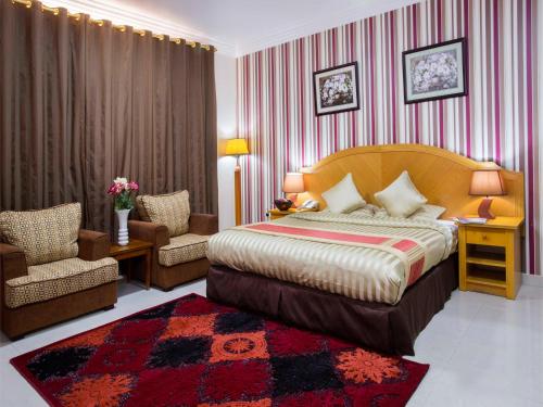 a hotel room with a bed and a chair at Safeer Hotel Suites in Muscat