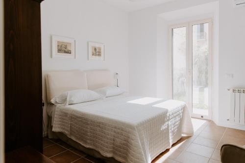 a white bedroom with a bed and a window at Casa Vacanze Bottasso 68 in Terracina