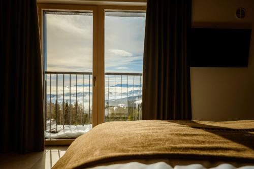 a bedroom with a bed and a large window at Hotel Panorama Kope in Šmartno pri Slovenj Gradcu