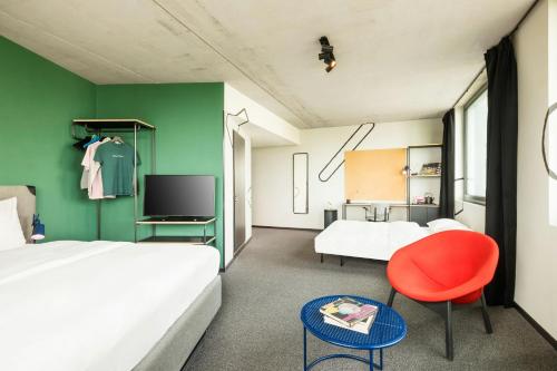 a bedroom with a bed and a red chair at The Social Hub Berlin Alexanderplatz in Berlin