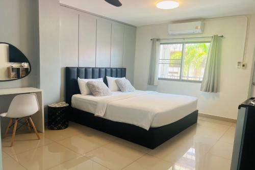 a bedroom with a bed with white sheets and a window at Dad N Mom's House By Thongnak Apartment in Pattaya