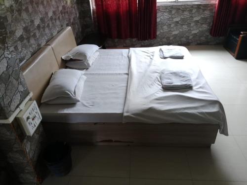 a bed with white sheets and pillows in a room at countryside view hotel Silchar in Silchar