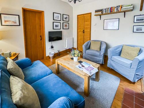 a living room with blue couches and a coffee table at Corner Cottage in Saxmundham