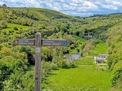 a street sign on a wooden pole in a valley at Parsley Cottage in Tideswell