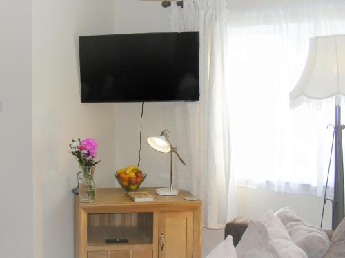 a living room with a tv and a table with a lamp at Chynoweth in Saint Merryn