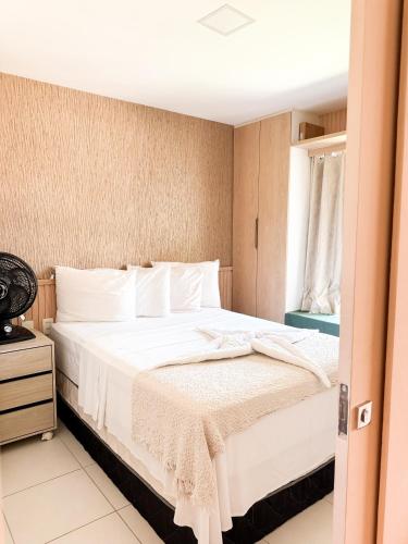 a bedroom with a bed with white sheets and a window at Vg Sun Cumbuco 112 in Caucaia