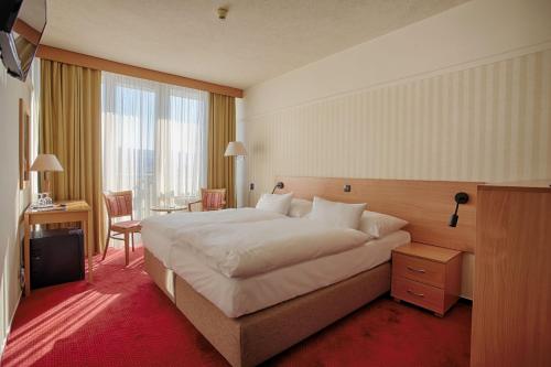 a hotel room with a large bed and a desk at Ensana Esplanade in Piešťany